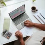 Woman working on laptop and calculator at a desk