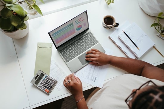 Woman working on laptop and calculator at a desk